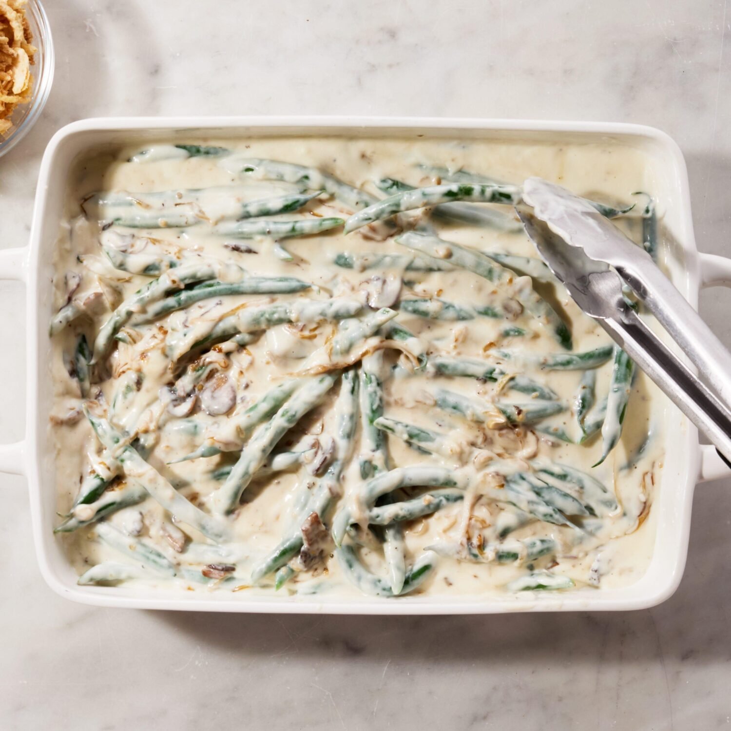 Green bean casserole mixture in a ceramic baking dish before baking.