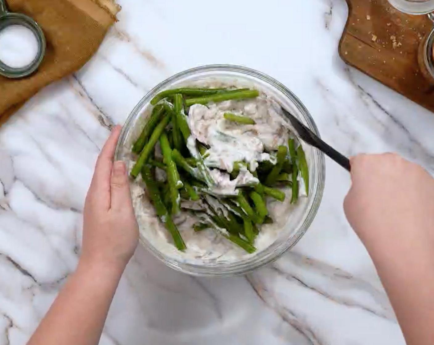 Green beans coated in creamy mushroom sauce before baking.