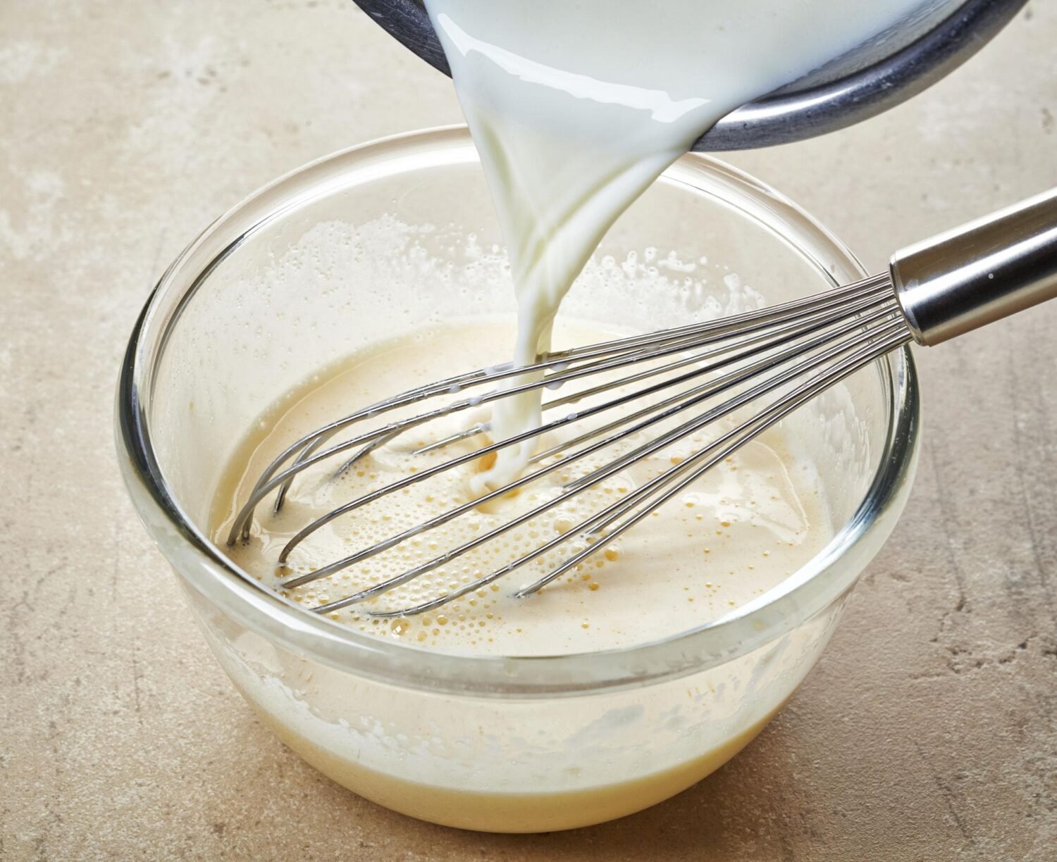 Cream of mushroom soup and milk mixed to prepare green bean casserole sauce.